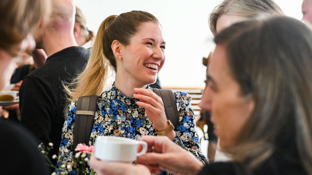 Registertage 2025 Eine lachende Frau mit geblümten Oberteil zwischen mehreren anderen Menschen