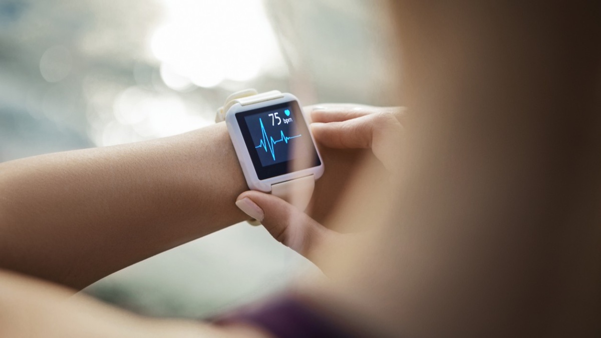 Nahaufnahme einer Smartwatch am Handgelenk. Auf dem Display werden eine Herzfrequenz von 75 Schlägen pro Minute und eine Herzkurve angezeigt.