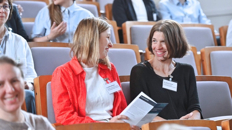 Zwei Frauen im Publikum, die sich lächelnd unterhalten.