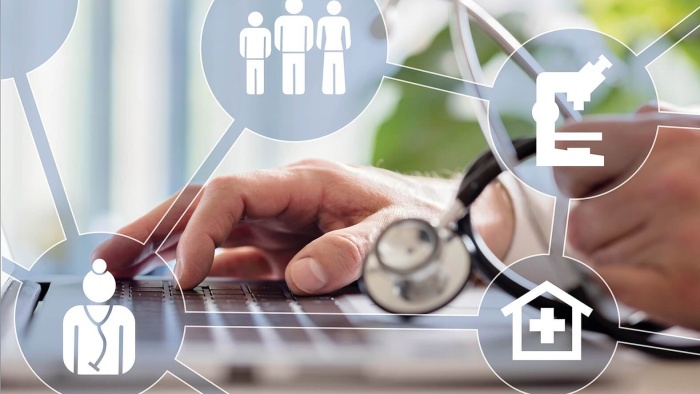 Hand einer Person mit Stethoskop tippt auf Laptop-Tastatur, umgeben von medizinischen Symbolen wie Arzt, Mikroskop, Krankenhaus und Personen-Icons.