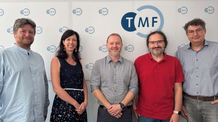 Fünf Personen, die vor einer Wand mit TMF-Logos stehen, lächeln in die Kamera.