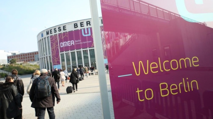 The Messe Berlin from the outside. On the left, people can be seen walking toward the building; on the left, a banner reads “Welcome to Berlin.”