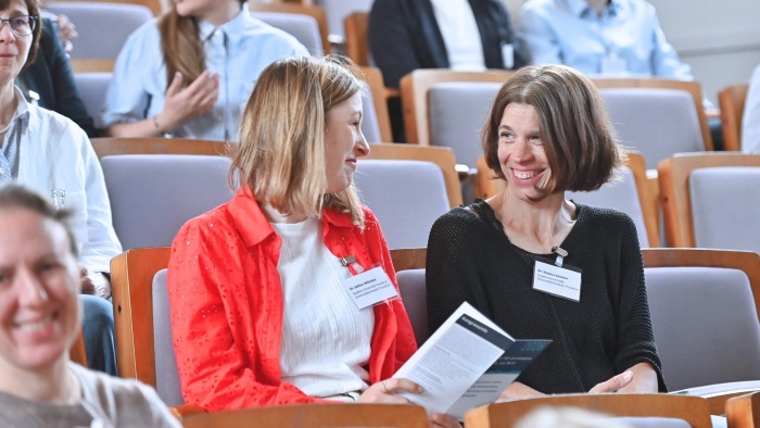 Zwei Frauen im Publikum, die sich lächelnd unterhalten.
