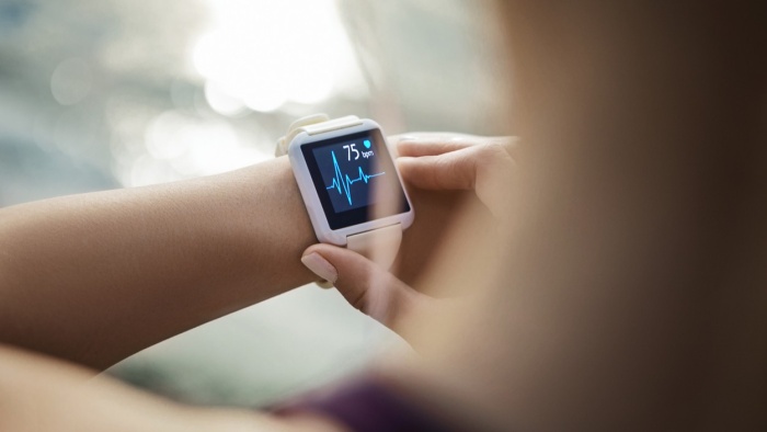 Nahaufnahme einer Smartwatch am Handgelenk. Auf dem Display werden eine Herzfrequenz von 75 Schlägen pro Minute und eine Herzkurve angezeigt.